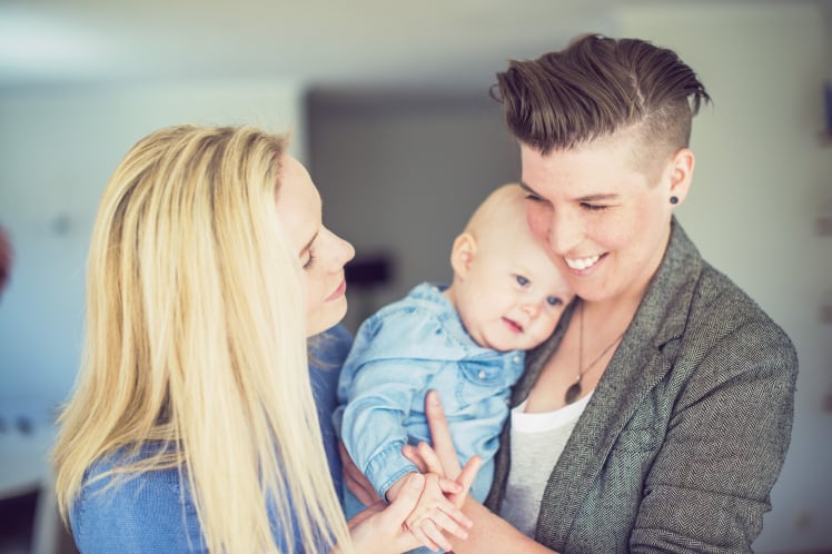 Happy young lesbian couple with baby at home | Dowson Turco